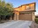 A tan two-story house featuring a stone column and a two-car garage door at 2665 E Gillcrest Rd, Gilbert, AZ 85298