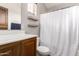 A well-lit bathroom has a wood vanity with a white countertop and a toilet near the shower with a white curtain at 2727 N Price Rd # 3, Chandler, AZ 85224