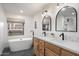 Elegant bathroom featuring a soaking tub, double vanity with stylish mirrors, and modern fixtures under a window with outside view at 28990 N White Feather Ln # 121, Scottsdale, AZ 85262