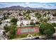 Expansive aerial view showcasing a tennis court and residences against a backdrop of majestic mountains at 3029 W Sierra St, Phoenix, AZ 85029