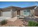 Inviting single-story home featuring a three-car garage, desert landscaping, and comfortable front porch seating at 3117 S Signal Butte Rd # 484, Mesa, AZ 85212