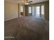 A large living room featuring neutral walls, carpet flooring, and a sliding glass door to the backyard at 3700 E Sandwick Dr, San Tan Valley, AZ 85140