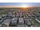 An aerial view showing a residential neighborhood with homes featuring solar panels and tiled roofs, set against a sunset sky at 4115 S 180Th Dr, Goodyear, AZ 85338