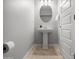 Clean powder room with a pedestal sink, round mirror, light fixtures, and tile flooring at 4115 S 180Th Dr, Goodyear, AZ 85338