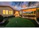 Spacious backyard featuring a putting green, covered patio with comfortable seating, and meticulously manicured landscaping at 4450 S Frequency --, Mesa, AZ 85212
