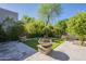Landscaped backyard with stone fountain, artificial grass, paved patio, and lush landscaping for outdoor enjoyment at 7296 E San Alfredo Dr, Scottsdale, AZ 85258
