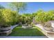 Charming backyard with artificial grass, a stone fountain, and planter pots amidst vibrant green trees at 7296 E San Alfredo Dr, Scottsdale, AZ 85258
