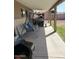 Covered patio area features a metal swing, concrete flooring, and an off-road vehicle in the background at 7901 W Tuckey Ln, Glendale, AZ 85303