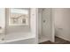 Bright bathroom showcasing tub, shower, and window with neighborhood views at 829 E Agua Fria Ln, Avondale, AZ 85323
