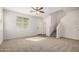 Bright living room with neutral carpet, white walls, ceiling fan, and stairs to the upper level at 829 E Agua Fria Ln, Avondale, AZ 85323