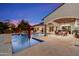 Stunning backyard pool at dusk featuring an umbrella, outdoor kitchen, and covered patio area at 8515 E Sutton Dr, Scottsdale, AZ 85260