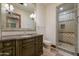 Well-lit bathroom with a green vanity, granite countertop, a large mirror, and a glass-enclosed shower at 8515 E Sutton Dr, Scottsdale, AZ 85260