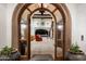 Grand foyer featuring stone archway, hardwood floors, and a glimpse of the living room and pool at 8515 E Sutton Dr, Scottsdale, AZ 85260