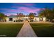 Stunning front exterior of home with manicured lawn, stone walkway, and beautiful desert landscaping at dusk at 8515 E Sutton Dr, Scottsdale, AZ 85260