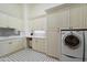 Bright laundry room with custom cabinets, ample counter space, a sink, and modern appliances for efficient chores at 8515 E Sutton Dr, Scottsdale, AZ 85260