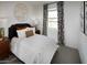 Well-lit bedroom showcases a bed with stylish pillows, decorative wall art, and large windows with patterned curtains at 8954 W Albeniz Pl, Tolleson, AZ 85353