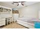 Bright bedroom with wood floors, ceiling fan, built-in desk, and a TV mounted above the dresser at 9021 W Elm St # 7, Phoenix, AZ 85037