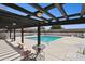 Community pool with blue water, deck chairs, and a wooden pergola providing shade at 9021 W Elm St # 7, Phoenix, AZ 85037