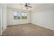 Bright bedroom with carpet flooring, ceiling fan, and large window with neighborhood view at 9234 W Hedge Hog Pl, Peoria, AZ 85383