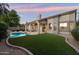 Inviting backyard featuring a private pool, covered patio, and green synthetic grass at 14424 N 64Th Pl, Scottsdale, AZ 85254