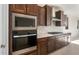Modern kitchen with built-in stainless microwave and oven and dark wood cabinets and drawers at 21278 N 272Nd Ave, Buckeye, AZ 85396