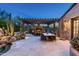 Relaxing outdoor patio with covered seating area, fireplace, dining table, and lush desert landscaping at 10057 E Blue Sky Dr, Scottsdale, AZ 85262
