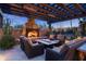Inviting outdoor seating area with fireplace, pergola, and comfortable wicker furniture for relaxation at 10057 E Blue Sky Dr, Scottsdale, AZ 85262