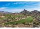 Aerial view of a beautiful desert golf course surrounded by custom homes with mountains in the distance at 10057 E Blue Sky Dr, Scottsdale, AZ 85262
