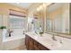 Bathroom featuring double sinks, a bathtub, and a window with privacy glass at 10224 S 175Th Ave, Goodyear, AZ 85338