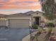 Charming single-story home with a neutral color palette and well-manicured desert landscaping at sunset at 10224 S 175Th Ave, Goodyear, AZ 85338