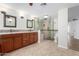 Bathroom with double sinks, wood cabinets, tiled walls, glass shower, tile floors, and modern fixtures at 14815 N 21St St, Phoenix, AZ 85022