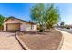 Low angle of charming single-story home featuring desert landscaping, mature trees, and a two car garage at 14815 N 21St St, Phoenix, AZ 85022