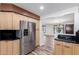 Kitchen with stainless steel refrigerator and wood cabinets opens into a living room with a dark-wood door at 14815 N 21St St, Phoenix, AZ 85022