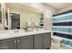 A well-lit bathroom featuring a double vanity, a large mirror, and a shower with a striped curtain at 1635 N 208Th Ave, Buckeye, AZ 85396