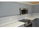 Close-up of a kitchen with gray cabinets, stainless steel appliances, and sleek white countertops at 17810 W Marshall Ln, Surprise, AZ 85388