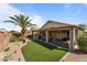 Inviting backyard featuring a covered patio, lush artificial turf, and a beautiful palm tree at 18058 W Weatherby Dr, Surprise, AZ 85374