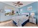 Bright bedroom with wood floors, ceiling fan and lots of windows overlooks the neighborhood with palm trees at 18058 W Weatherby Dr, Surprise, AZ 85374