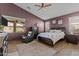 The primary bedroom is brightly lit with three windows, features a ceiling fan and is decorated with an area rug at 18058 W Weatherby Dr, Surprise, AZ 85374