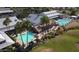 Aerial view of the community clubhouse and pools with palm trees and lounge seating at 18058 W Weatherby Dr, Surprise, AZ 85374