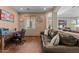 Cozy living room features an archway, brown leather sofa, desk with office chair, and wood-look flooring at 18058 W Weatherby Dr, Surprise, AZ 85374