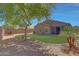 Backyard features a grassy area with trees, flowerbed, and patio furniture set against a brick wall backdrop at 18590 W Vogel Ave, Goodyear, AZ 85338