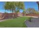 Backyard view showing gravel landscaping, grassy area, trees, and brick perimeter fence at 18590 W Vogel Ave, Goodyear, AZ 85338