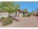 Front view of a charming single-story home with desert landscaping, manicured bushes, and a covered front porch at 18590 W Vogel Ave, Goodyear, AZ 85338