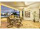 Covered patio with brick flooring and wrought iron table set, offers relaxing outdoor living with sunset views and a glimpse of the pool at 21474 N 56Th Ave, Glendale, AZ 85308