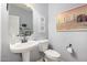 Cozy half-bathroom with a pedestal sink, framed artwork, and light blue walls at 2553 E Carob Dr, Gilbert, AZ 85298