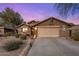 Charming home featuring a two-car garage, desert landscaping, and a welcoming front entry during a peaceful twilight at 25821 N 41St Dr, Phoenix, AZ 85083