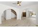 Bright living room with wood-look flooring, a ceiling fan, and arched entryways to the stairs and front door at 2619 S Los Altos --, Mesa, AZ 85202