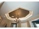 Dining room ceiling with elegant chandelier and decorative tray ceiling design at 27083 W Marco Polo Rd, Buckeye, AZ 85396