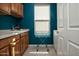 A bright laundry room with blue walls, light wood cabinets, and a utility sink at 27083 W Marco Polo Rd, Buckeye, AZ 85396