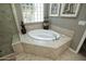 Luxurious soaking tub with tile surround and a decorative glass block window at 27083 W Marco Polo Rd, Buckeye, AZ 85396